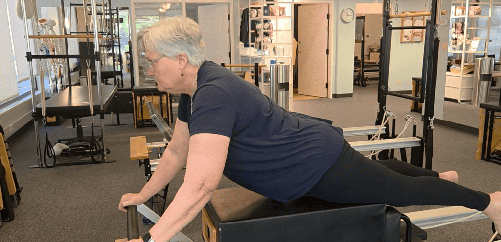 Pilates client Angie Moore performing a Swan Dive modification on the Reformer at Pacific Northwest Pilates in Portland, Oregon